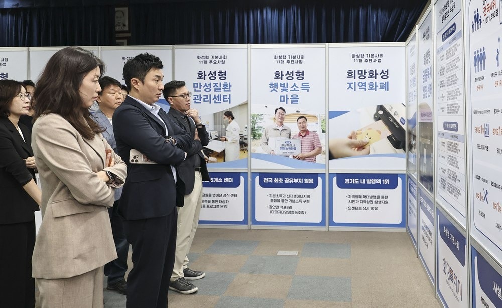 Members of the Hwaseong-type Basic Society Committee examine exhibition materials introducing major policies. Provided by Hwaseong City