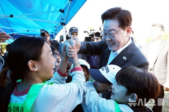 [Iksan=Newsis] Phóng viên Kim Jin-ah = Tổng thống Lee Jae-myung đang chào hỏi các học sinh trong Lễ hội thể thao Trường hạnh phúc mùa thu diễn ra tại Trường tiểu học Wanggung, Iksan, Tỉnh Bắc Jeolla vào ngày 22. 2026.10.22. bluesoda@newsis.com